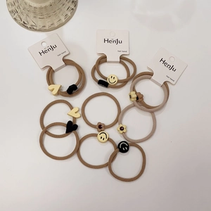 Close-up of brown hair ties featuring resin heart, smiley face, and flower ornaments