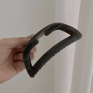 Dettaglio macro della grande molletta per capelli in acrilico nero traslucido con molla