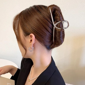 Detail view of a large silver metal shark hair claw clip securing a long brown updo