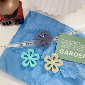 Detailed view of flower hair claws in lavender, mint green and cream on blue background