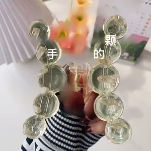 Close-up of a translucent light green acrylic hair claw clip with round bead design