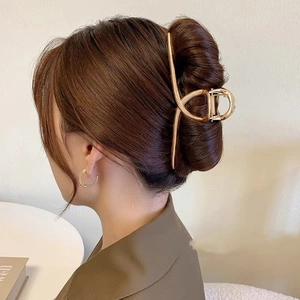 Detail shot of a large gold metal hair claw clip holding hair in an elegant updo