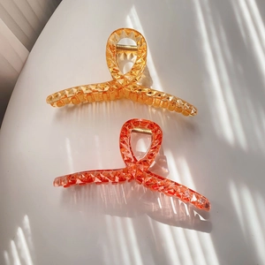 Detail of amber and coral shark hair clips featuring diamond-cut resin and metal springs