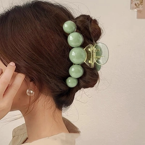 Large light green acrylic hair claw with five big pearls on model in side-rear view