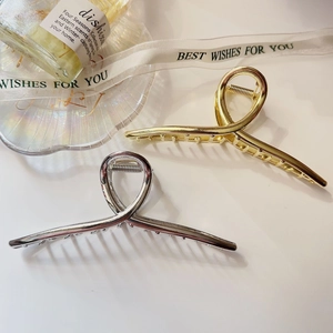 Detail view of large gold and silver metal claw clips with minimalist twisted design