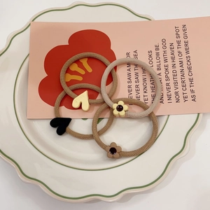Set of elastic hair ties featuring heart and flower charms on a decorative white ceramic plate