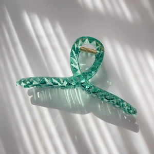 Detail of mint green crystal acrylic hair claw clip with geometric prism cutting design