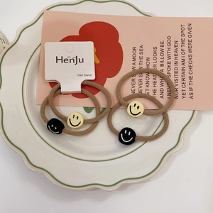 Close-up of ribbed hair bands with smiling face charms on a white ceramic plate