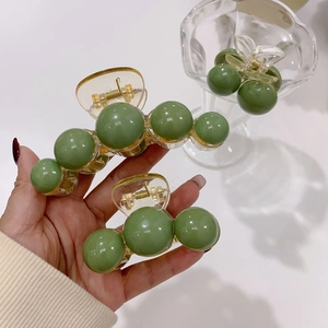 Close-up of olive green acrylic hair claw clips with marble texture spherical beads