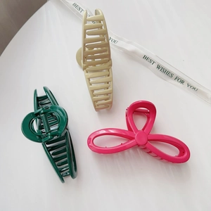 Close-up of stylish large hair claws in beige, dark green, and magenta colors