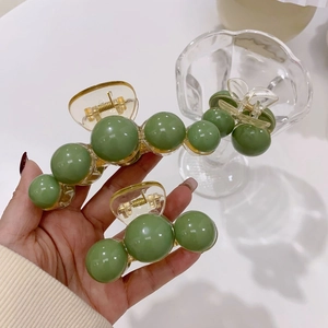 Detail of green acrylic pearl hair claw clips in large and small sizes with gold springs