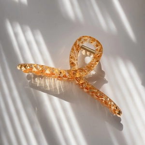Detailed view of amber transparent acrylic hair claw with geometric cuts and gold spring