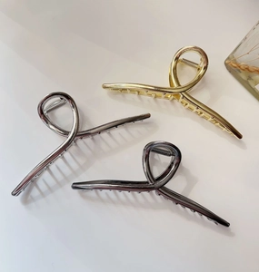 Three large metal claw clips in gold, silver, and grey on a clean white surface