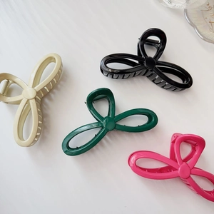 Detailed view of large hair claw clips in beige, black, green and hot pink colors
