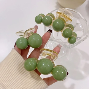 Detail of Morandi green acrylic shark clip with smooth pearls and golden spring