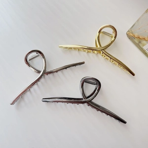 Three minimalist metal hair claw clips in gold, silver and dark grey on white background