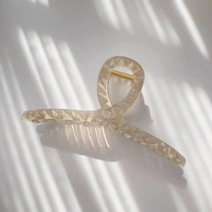 Detailed view of the champagne translucent shark clip with diamond-cut geometric texture