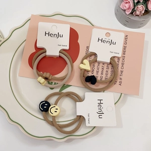 Minimalist elastic hair ties featuring heart, smile, and flower charms in earthy tones