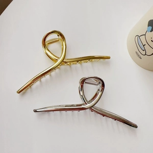 Detailed view of large gold and silver metal hair claws with elegant twisted design