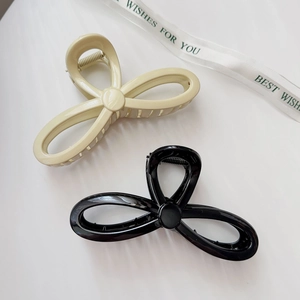 Detail view of interlocking bow-shaped hair claws in black and beige finishes