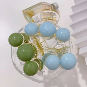 Macro view of pastel acrylic pearl hair claws with gold metal springs in a glass
