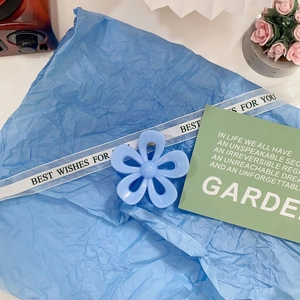 Close-up of blue floral hair claw clip on decorative paper with elegant ribbons