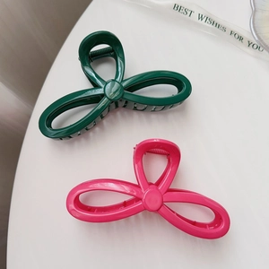 Close-up of elegant dark green and pink bow hair claws on a clean white surface