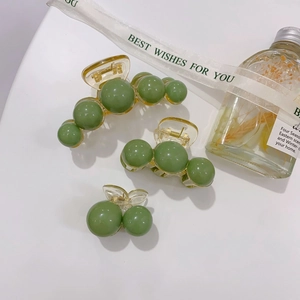 Detailed set of three green pearl acrylic hair claws in small, medium, and large sizes