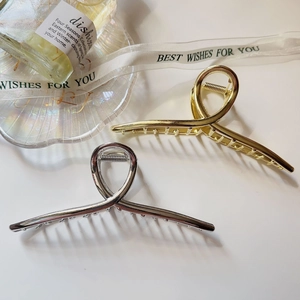 Detailed view of large gold and silver metal hair claws with minimalist knot design