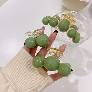 Detailed set of three green acrylic pearl hair claws with transparent amber grips
