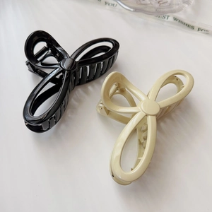 Detail of minimalist bow-shaped hair claws in black and cream with strong metal teeth