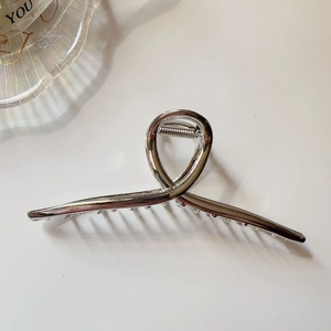 Detailed top view of large silver metal hair claw clip with cross twist geometric design