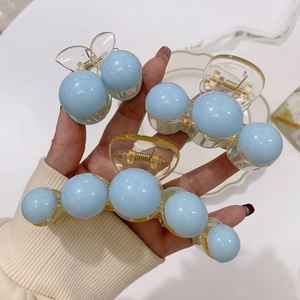Close-up of three light blue acrylic hair claws with smooth sphere beads and metal spring