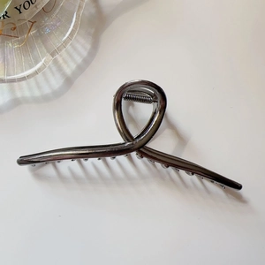 Detail of gunmetal grey metal hair claw clip with cross loop design and fine teeth