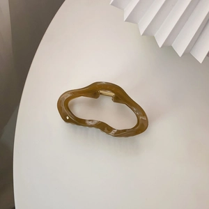 Detailansicht der bernsteinfarbenen Haarklammer in Wolkenform mit Goldfeder