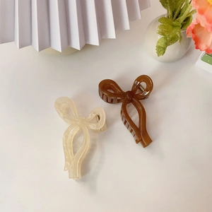 Close-up of jelly-colored bow hair claws in cream and brown with metal spring detail
