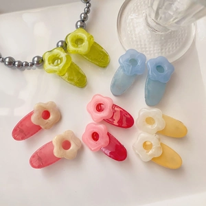 Detailed macro shot of acetate flower hair clips in vibrant colors on a white tray