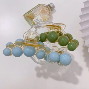 Close-up of acrylic pearl claw clips in Morandi blue and avocado green on white table