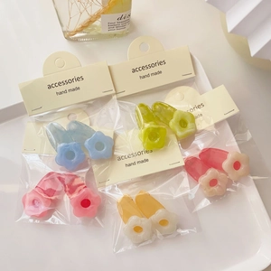 Macro detail of five pairs colorful resin flower hair clips in various pastel shades