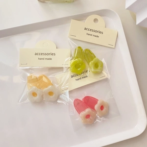 Chic floral hair clips in green, yellow and pink colors on a white minimalist tray