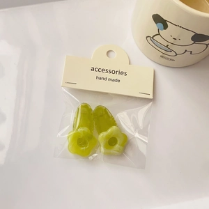 Detailed close-up of grass green flower-shaped hair clips in handmade cardboard packaging