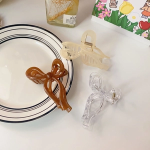 Glossy jelly-colored bow hair clips in dark brown, cream, and clear with gold springs