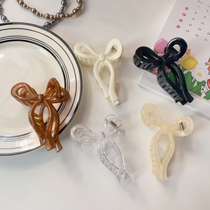 Detailed view of jelly color bow hair claws in five shades on a decorative tabletop