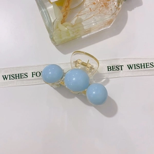 Detail of transparent acrylic hair claw with blue pearls and sturdy metal spring clip