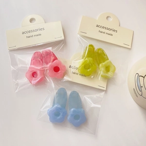 Close-up of three pairs of translucent floral hair clips in pink green and blue