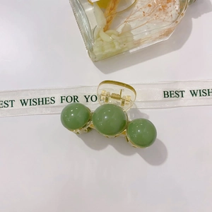Detail of light green acrylic hair claw clip with transparent base and golden spring