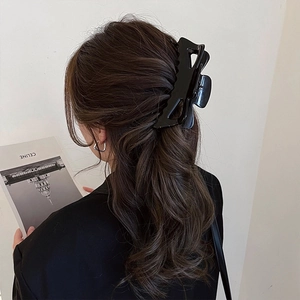 Détail d'une grande pince à cheveux noire ajourée portée sur des cheveux bruns