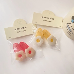 Close-up of floral hair clips in pink and white resin on display cards