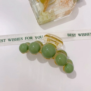 Detail of sage green acrylic pearl hair claw clip with transparent amber base frame