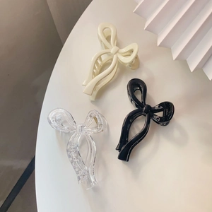 Bow claw clips in cream, black, and transparent colors on a minimalist background